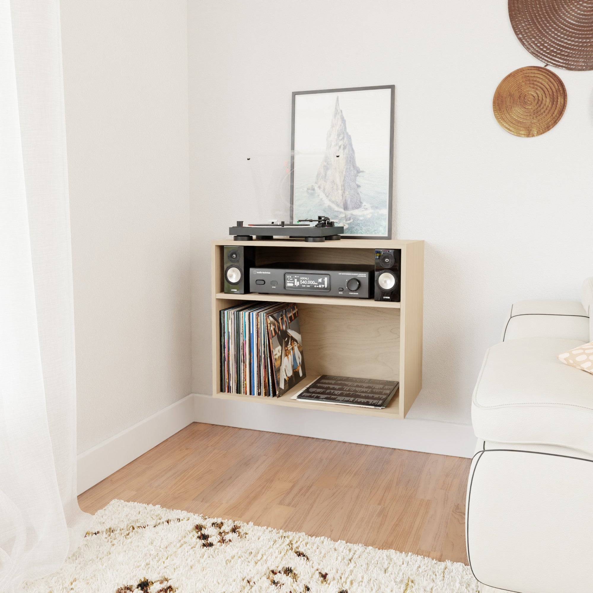 A modern corner setup with a turntable and audio equipment on a wooden shelf. A stack of vinyl records is stored below. A cozy white couch and a textured rug complete the space, with decorative wall accents.