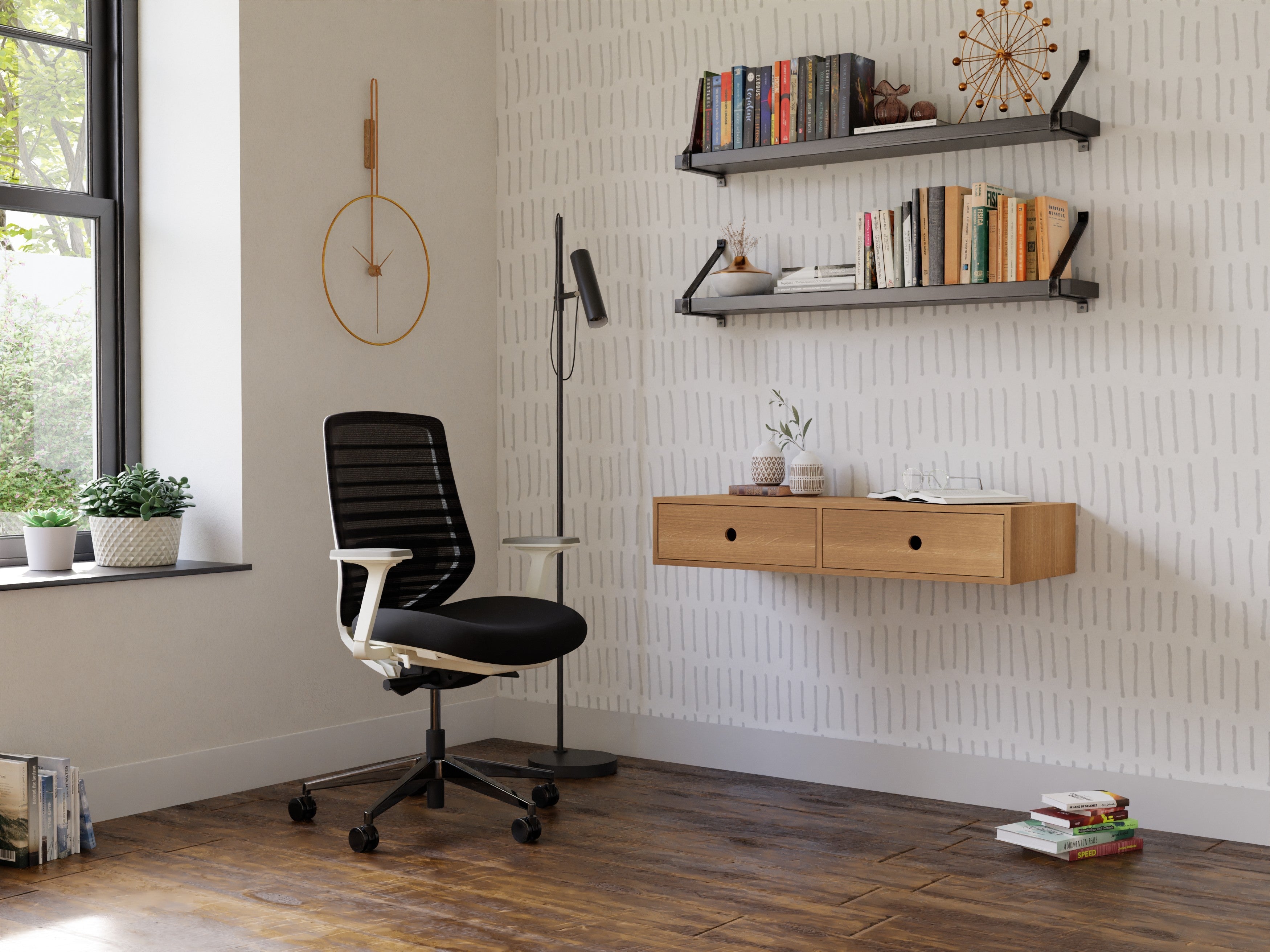 A modern home office with a black swivel chair, a wooden floating desk, two shelves with books and decor, a standing lamp, and a large window. The walls are light with a subtle geometric pattern.