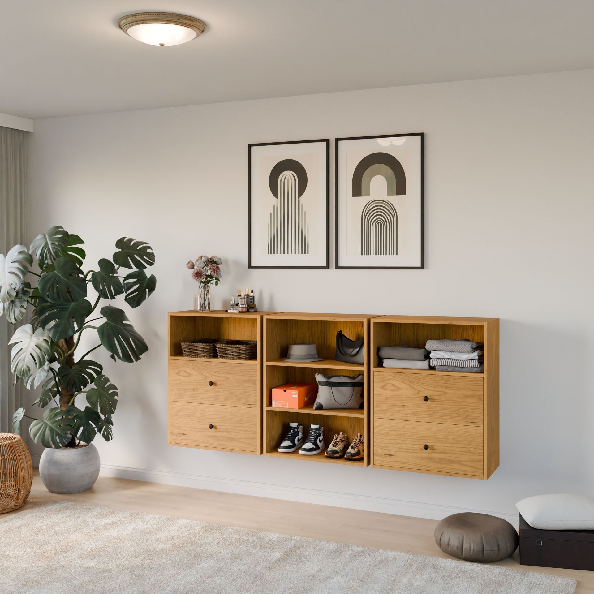 A minimalist room presents Krovel Furniture Co.'s Closet Drawers and Shelves in Cherry, showcasing clothes, shoes, and décor. Above, two abstract artworks are displayed. Below them sit a potted plant and basket on the floor beneath the ceiling light. 