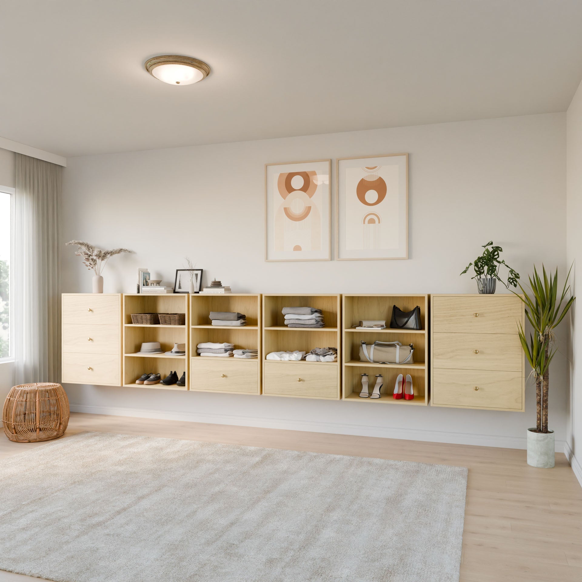 A minimalist bedroom showcases Krovel Furniture Co.'s Closet Drawers and Shelves in Maple, displaying clothes, shoes, and decor. Two abstract art pieces hang above. A large window with sheer curtains bathes the room in light. A wicker basket and potted plant complete the look. 