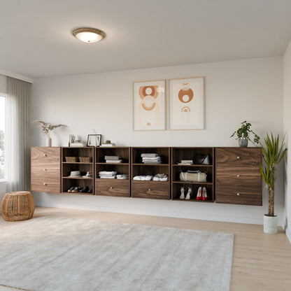 A modern room features Krovel Furniture Co.'s Closet Drawers and Shelves in Walnut, mounted on a white wall with clothes, shoes, and decor. Two abstract art pieces are above. A large rug covers the floor, while a plant and a wicker basket adorn the corners as light filters through a window. 