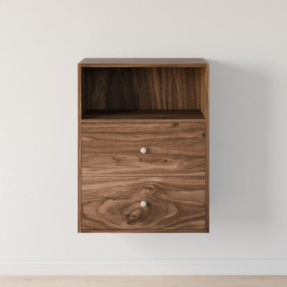 The Krovel Furniture Co.'s Closet Drawers and Shelves in Walnut features a wall-mounted wooden cabinet with a modular shelf, two drawers with silver knobs, natural grain texture, and dovetail construction. It complements light walls and floors, making it an elegant addition to any closet. 