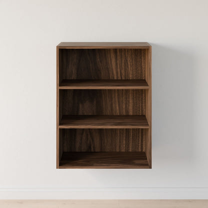 The Closet Drawers and Shelves in Walnut by Krovel Furniture Co. is a wall-mounted piece with three empty shelves, showcasing a dark wood finish and dovetail construction, featuring clean and simple lines against a plain white wall. 