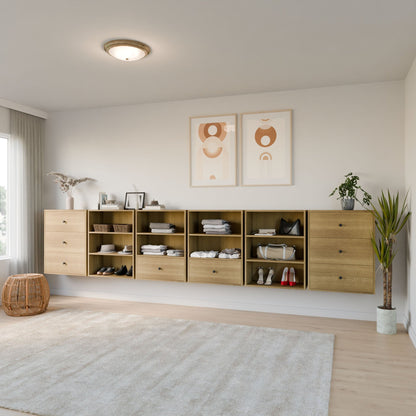 The spacious room showcases Krovel Furniture Co.'s Closet Drawers and Shelves in White Oak, with wooden floating shelves and drawers for clothes, shoes, and decor. Two abstract art pieces adorn the wall above. A potted plant and wicker basket add harmony in neutral tones under sheer-curtained windows. 