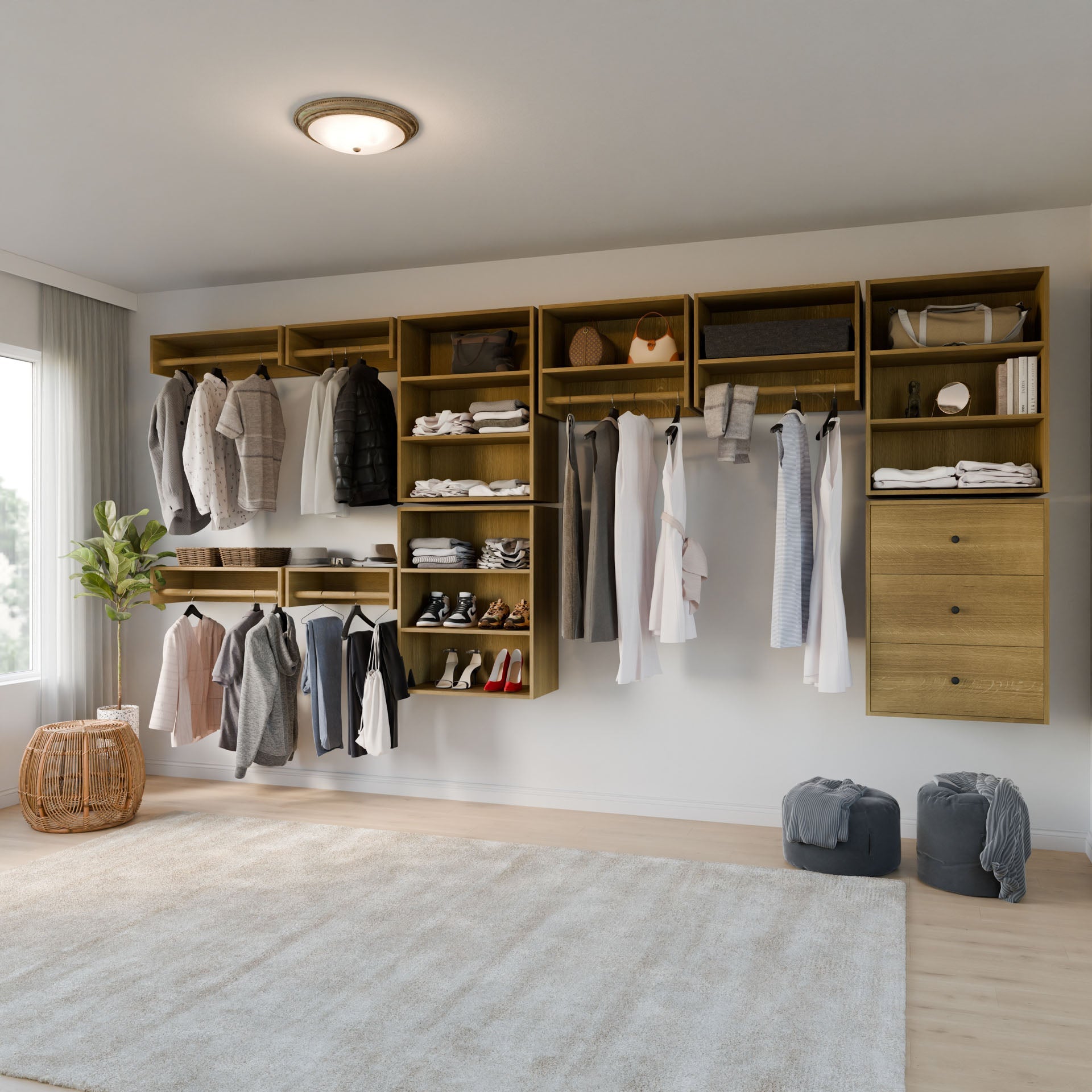 A minimalist walk-in closet showcases Krovel Furniture Co.'s Closet Drawers and Shelves in White Oak, featuring clothes, shoes, and accessories. Two poufs and a wicker basket adorn the floor, while soft natural light filters through a window onto the elegantly designed beige rug. 