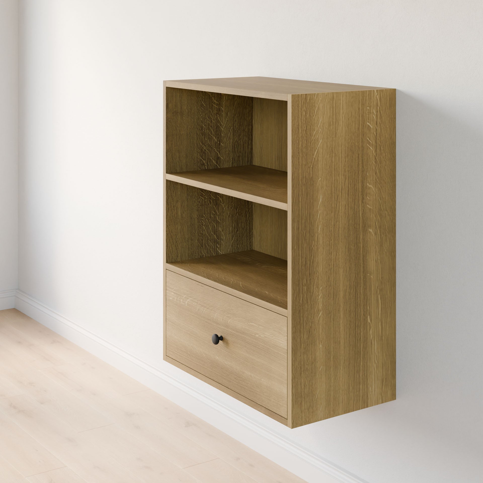 The Closet Drawers and Shelves in White Oak by Krovel Furniture Co. is a wooden, wall-mounted unit made from premium-grade plywood with two open shelves and a drawer with a round black knob, perfect for closet customization. It stands against light-colored walls and floors. 