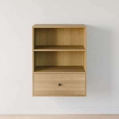 Krovel Furniture Co.'s Closet Drawers and Shelves in White Oak is a minimalist wall-mounted shelf crafted from premium-grade plywood. It features two open compartments, a drawer with a round black knob, and elegantly accents a plain white wall. 