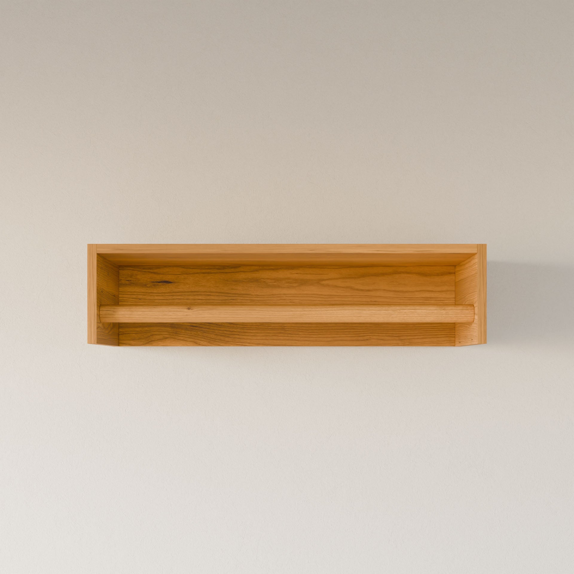 The Closet Hanger in Cherry by Krovel Furniture Co. is displayed on a plain, light-colored wall. Its simple, handmade wooden design offers a premium-grade look that casts a soft shadow behind it.