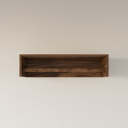 The Walnut Closet Hanger by Krovel Furniture Co. is a floating wooden shelf made from premium plywood with a simple rectangular design. Its natural wood grain pattern, complemented by a sleek hardwood veneer, offers an elegant and minimalistic look against a light beige wall.