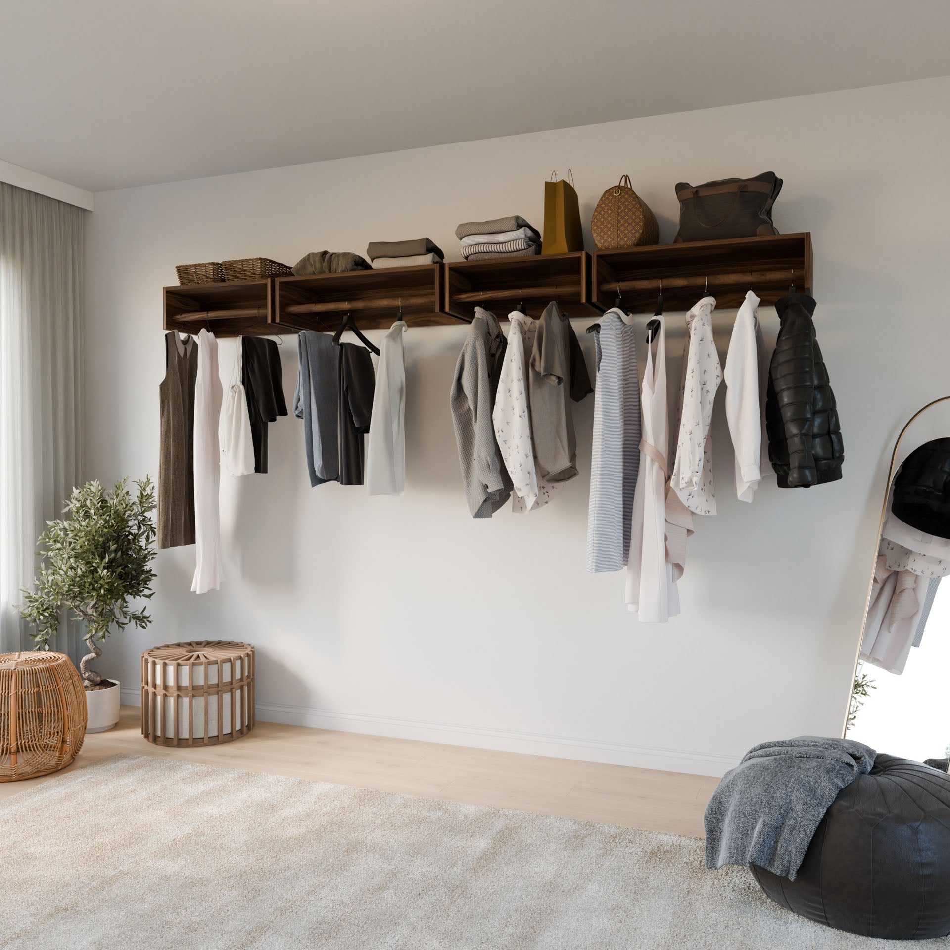 A minimalist bedroom includes a Krovel Furniture Co. Closet Hanger in Walnut displaying clothes in neutral tones. A large mirror leans against the wall, complemented by a potted plant, while a soft rug on the premium-grade plywood floor enhances the serene atmosphere.