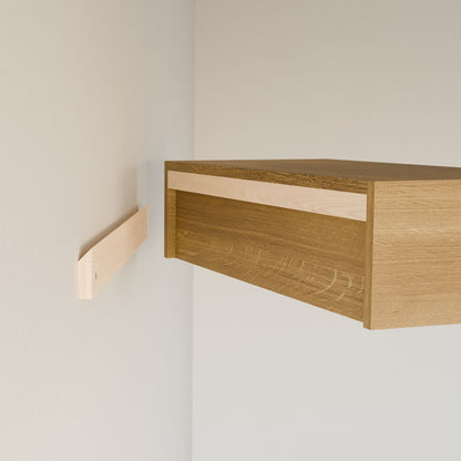 The Closet Hanger in White Oak by Krovel Furniture Co. is partially installed on a wall using a wooden mounting bracket, showing an open side. Handmade in Portland, Maine from premium cabinet plywood, the unfinished hanger awaits full installation.