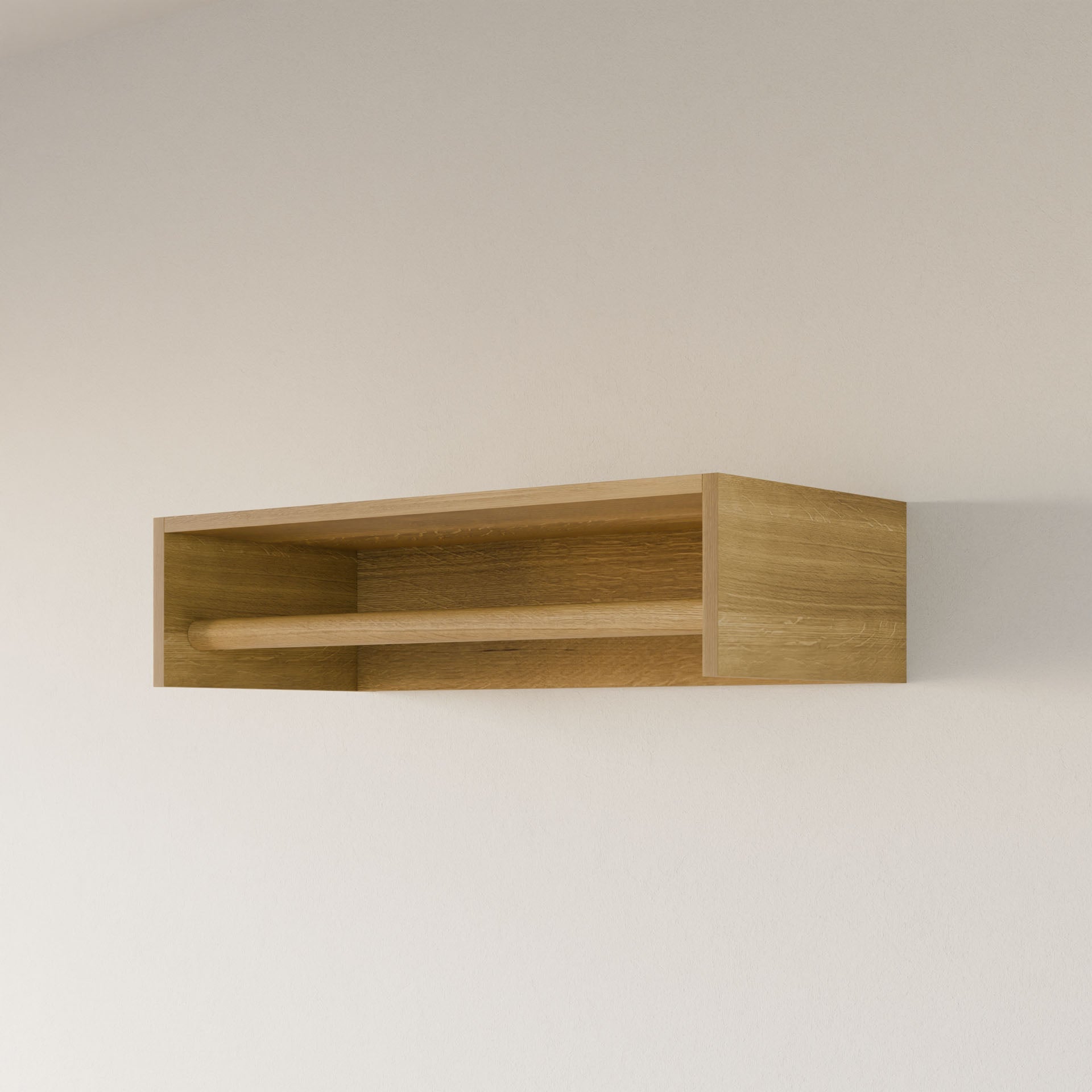 A Closet Hanger in White Oak by Krovel Furniture Co., handmade in Portland, Maine, is mounted on a beige wall. Featuring an open design with a horizontal bar across the front, it offers a simple and functional aesthetic.