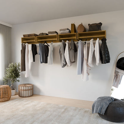 A minimalist bedroom features a Krovel Furniture Co. Closet Hanger in White Oak for shirts and jackets, a wall-mounted shelf with baskets, and a mirror reflecting the space. A potted plant and woven basket sit on the floor, with sunlight highlighting the premium cabinet plywood accents.