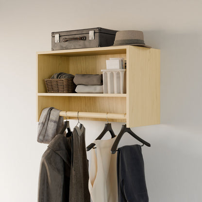 The Closet Hanger with Shelf in Maple by Krovel Furniture Co. is a handcrafted wooden wall-mounted shelf from Portland, Maine. It features open compartments that hold a suitcase, basket, folded clothes, and toiletries. Below, it displays garments on black hangers with a hat resting above its premium-grade cabinet plywood construction.