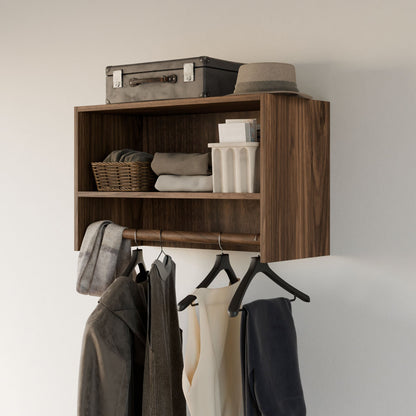 The Closet Hanger with Shelf in Walnut by Krovel Furniture Co. is crafted from premium plywood, holding a suitcase, clothes, a basket, a hat, and containers. It features a rod for hanging jackets and trousers below. This modular piece adds charm against light-colored walls.