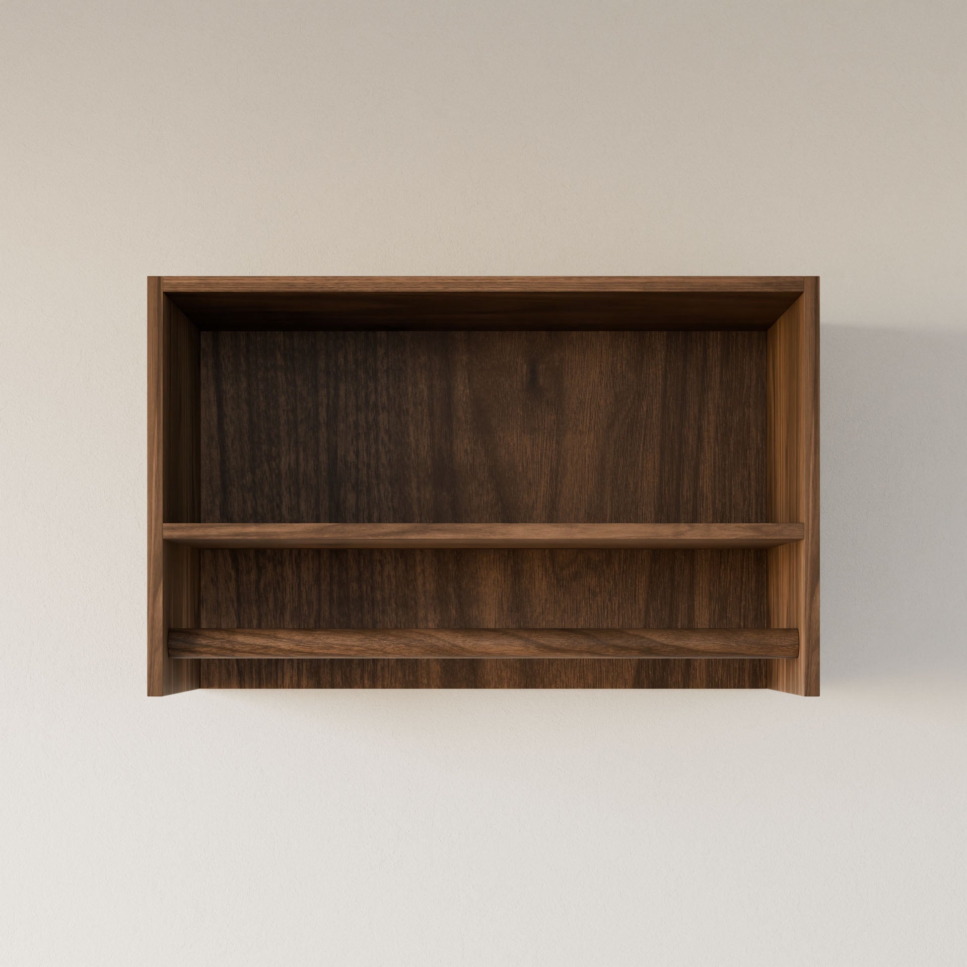 The Closet Hanger with Shelf in Walnut by Krovel Furniture Co. is a simple, handmade wooden shelf crafted in Portland, Maine. Featuring a premium-grade plywood finish and one horizontal divider, it showcases a natural dark grain pattern for an elegant touch against a plain light-colored wall.