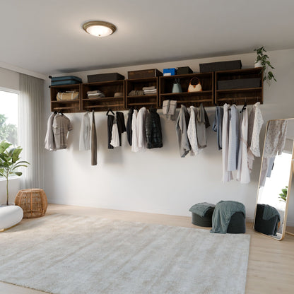 A minimalist room features clothes on a wall-mounted Krovel Furniture Co.'s Walnut Closet Hanger with Shelf, alongside a large beige rug, woven basket, plants, and pouf. A full-length mirror and blankets accompany the setup, with sheer curtains allowing soft natural light to enhance the serene vibe.