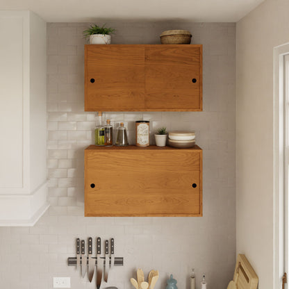 A modern kitchen wall showcases Krovel's Cupboard with Shelf in Cherry, adorned with potted plants and essentials. Below, knives are neatly organized on a magnetic strip beside cooking utensils on the counter, complemented by a sleek floating storage cabinet for extra convenience.