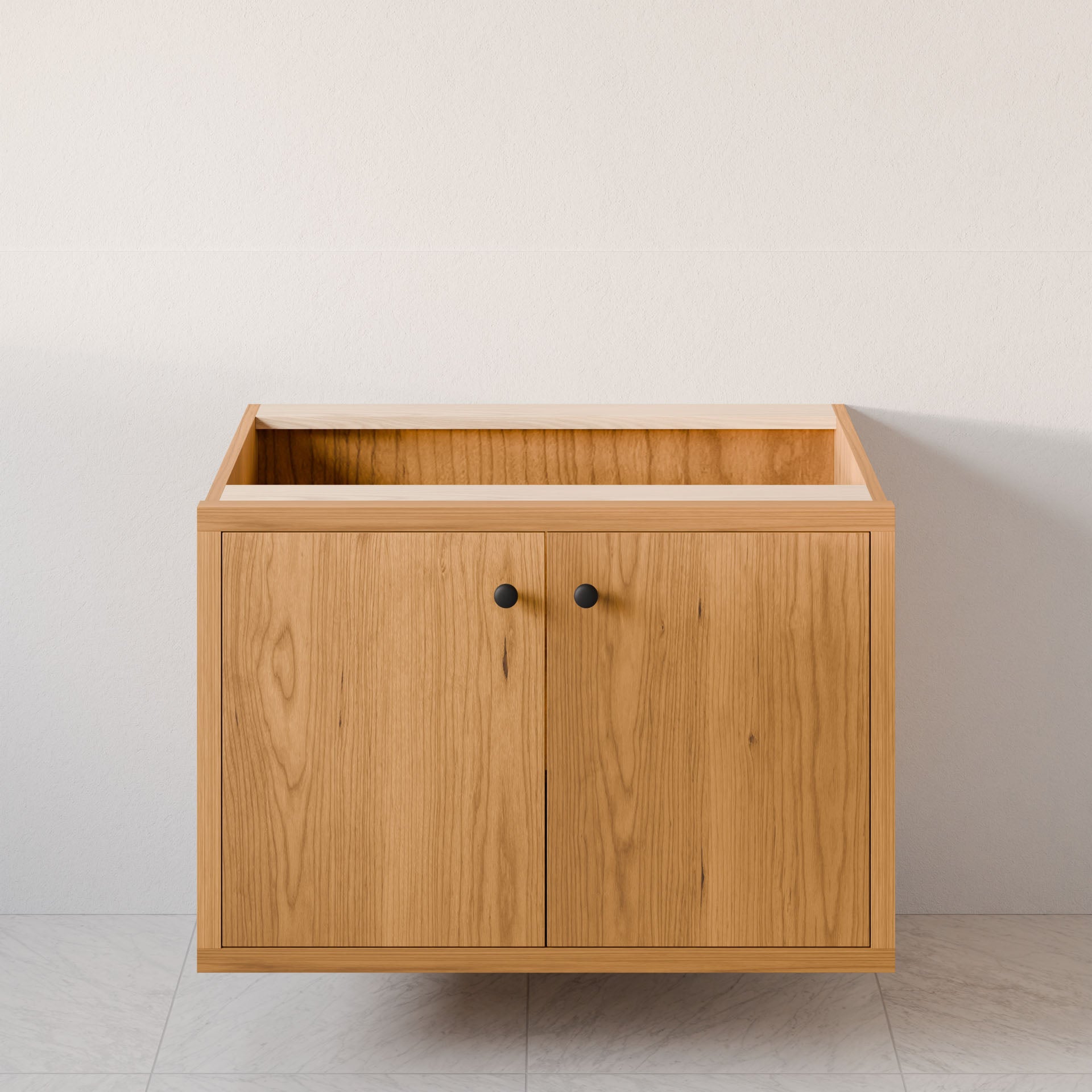 The Double Door Vanity in Cherry by Krovel Furniture Co. features a minimalist design with hardwood veneer, two doors with round black knobs, and soft-close hinges. Positioned against a neutral wall on a light tiled floor, it boasts an open top section for added convenience.