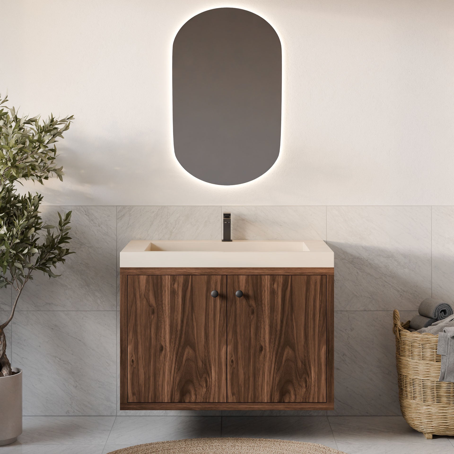 A modern bathroom showcases Krovel Furniture Co.'s Double Door Vanity in Walnut with soft-close hinges, an oval backlit mirror, and a beige countertop. Neutral tiles line the walls and floor. A woven towel basket is on the right, while a small tree provides greenery on the left.