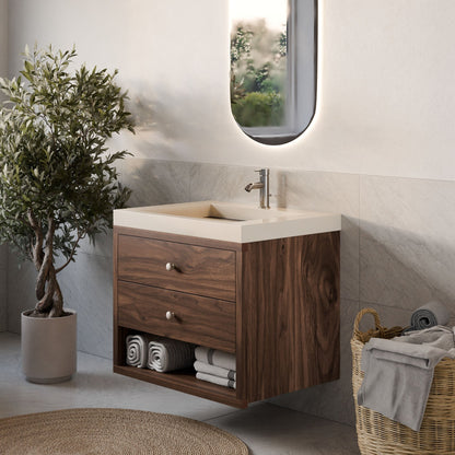 The stylish bathroom features a Krovel Furniture Co. floating Double Drawer, Open Shelf Vanity in Walnut with a white sink, an illuminated oval mirror above, neatly arranged towels below, a wicker basket with extra towels on the side, and a potted plant for decoration.