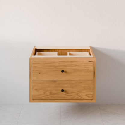 The Double Drawer Vanity in Cherry by Krovel Furniture Co. is a sleek wall-mounted bathroom piece with two drawers, hardwood veneer, and black knobs. Its natural wood finish complements light walls and tiled floors, with custom size options to fit any space perfectly.