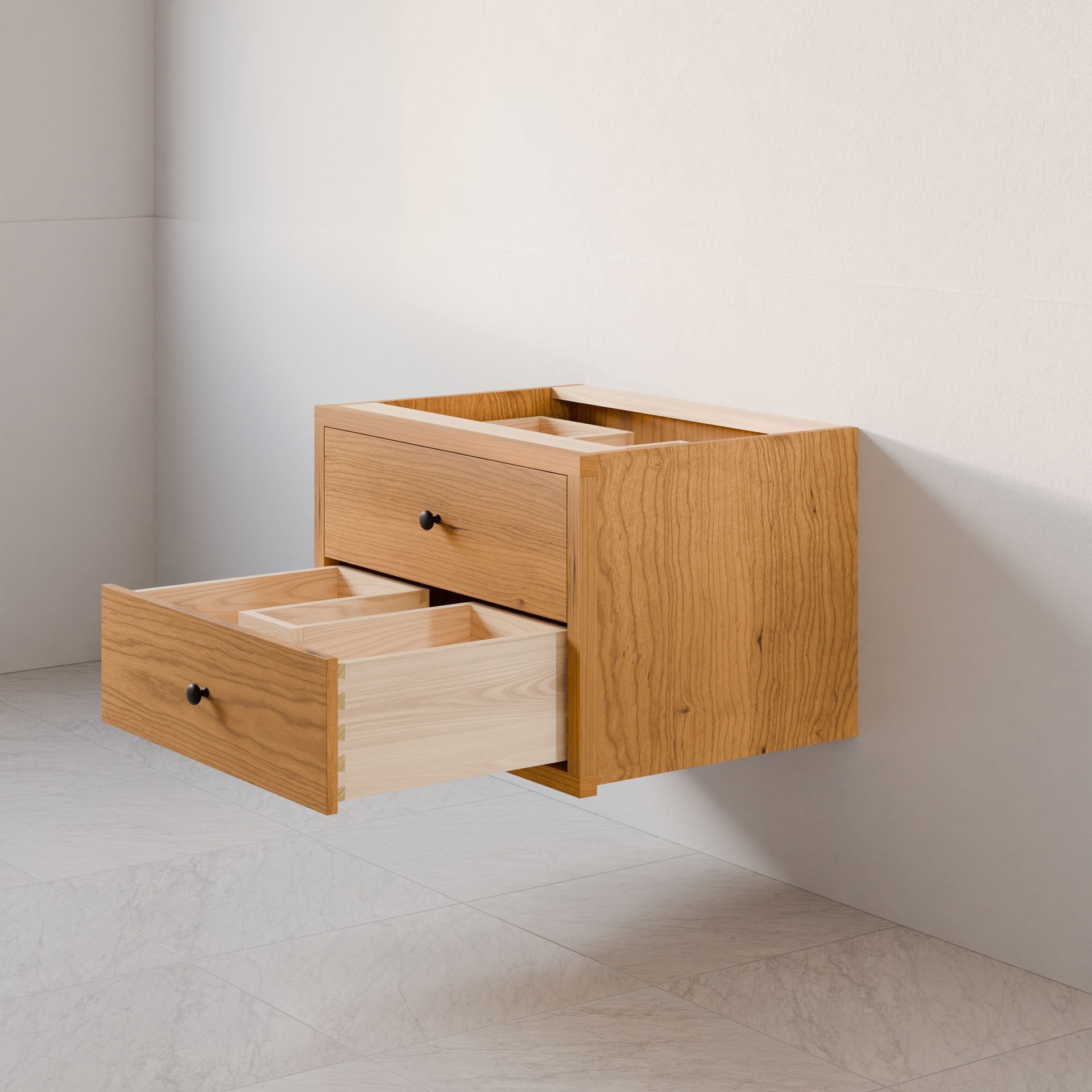 The Double Drawer Vanity in Cherry by Krovel Furniture Co. is mounted on a light wall, showcasing its floating wooden design with a hardwood veneer. One drawer is slightly open, revealing a partitioned light wood interior. Its sleek, minimalist aesthetic stands out against the tiled floor.