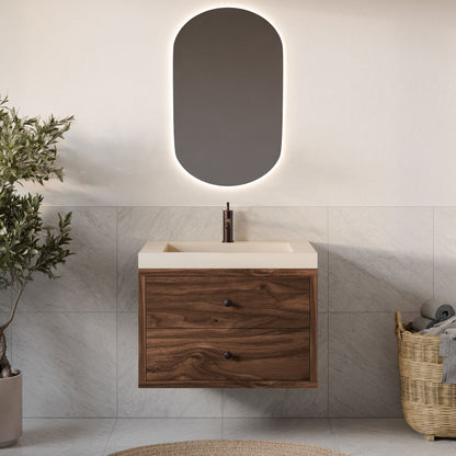 A modern bathroom features the Krovel Furniture Co. Double Drawer Vanity in Walnut with a sleek faucet and rectangular sink. An oval backlit mirror hangs above, and a basket with towels and a green plant completes the look against the light tiled wall.