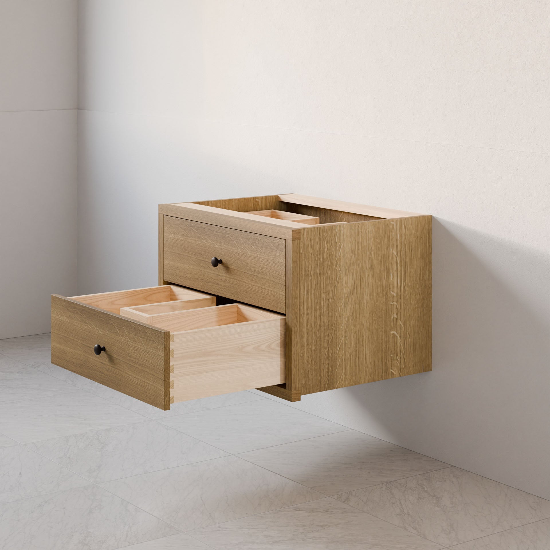 The Double Drawer Vanity in White Oak by Krovel Furniture Co. is a modern, wall-mounted cabinet with two soft-close drawers. It features a hardwood veneer and a contrasting light wood interior, creating an elegant look against light walls and tiled floors.