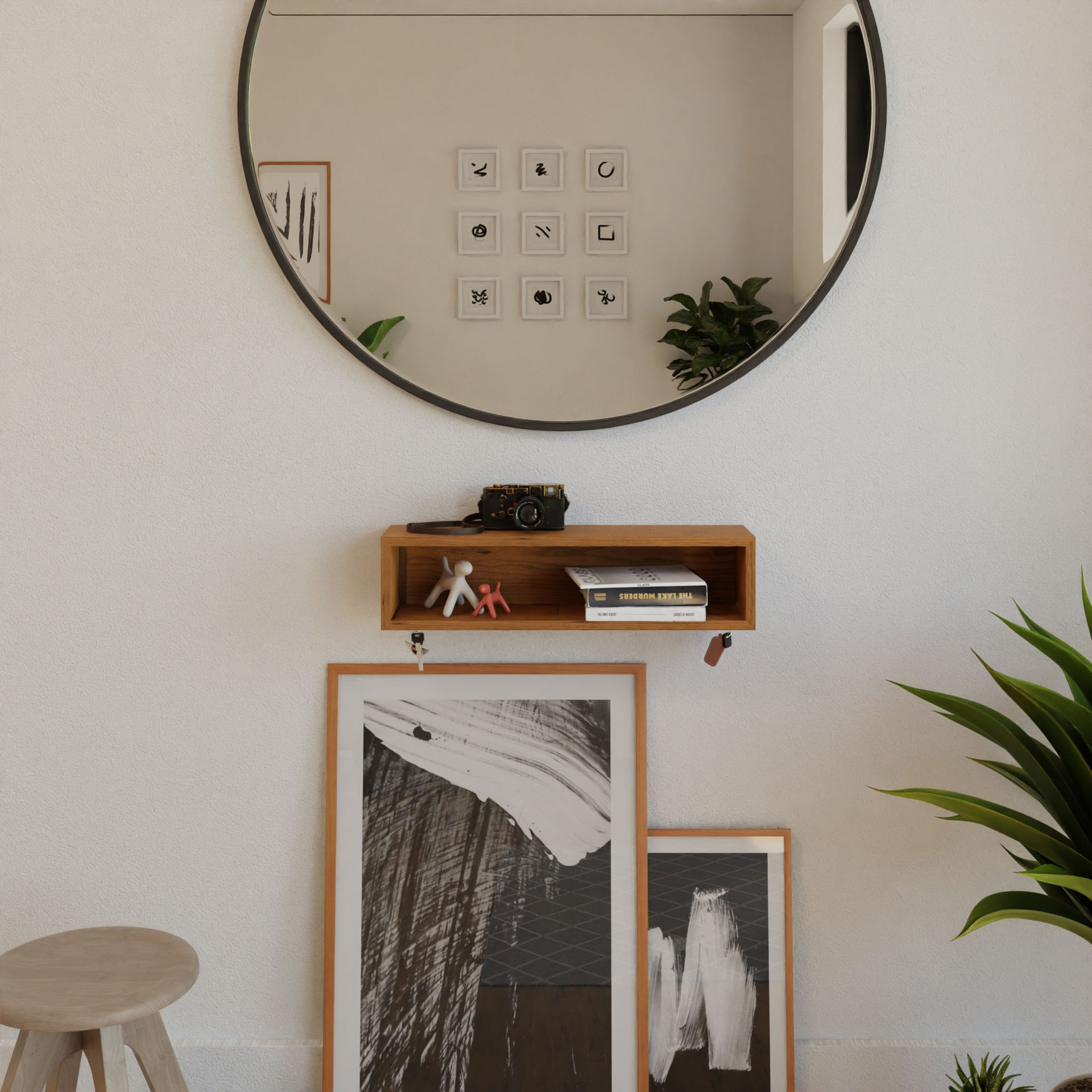 A room with a round wall mirror reflecting a potted plant features Krovel's Cherry Entryway Organizer holding a camera and books. Framed abstract art leans against the wall beside a small wooden stool, while a lush green plant sits to the right.