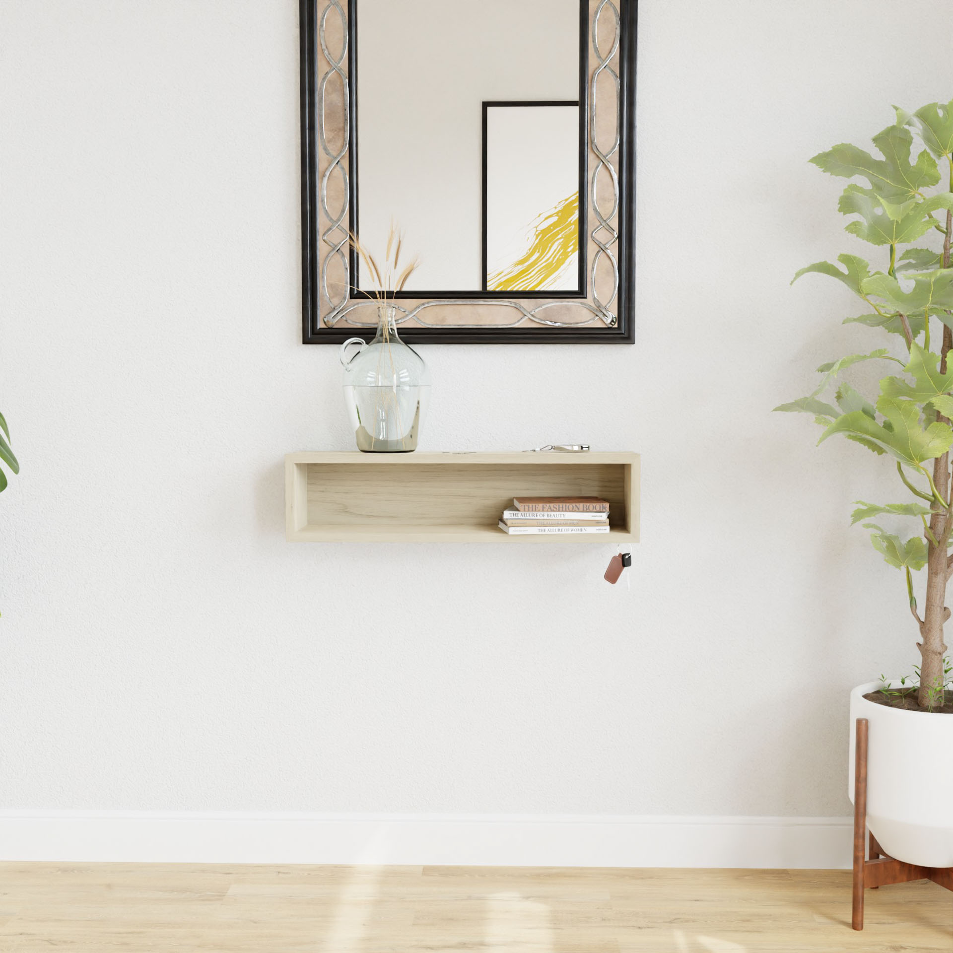 A minimalist living room showcases a Krovel Maple Entryway Organizer, elegantly mounted on the wall, displaying books and a small glass vase with dried flowers. Above it, a decorative mirror is securely attached to the white wall with a french-cleat mount. A potted plant is placed on the wooden floor next to the organizer.