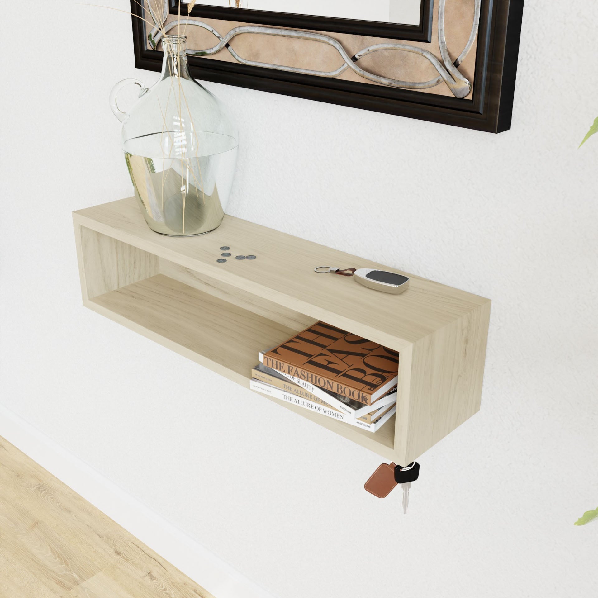 A minimalist floating entryway organizer by Krovel, crafted from Maple, is mounted on a white wall. On top, it holds a decorative glass jar, coins, a keychain, and a smartphone. Inside the organizer are three books. A set of keys hangs from a hook beneath the shelf using a secure french-cleat mount.