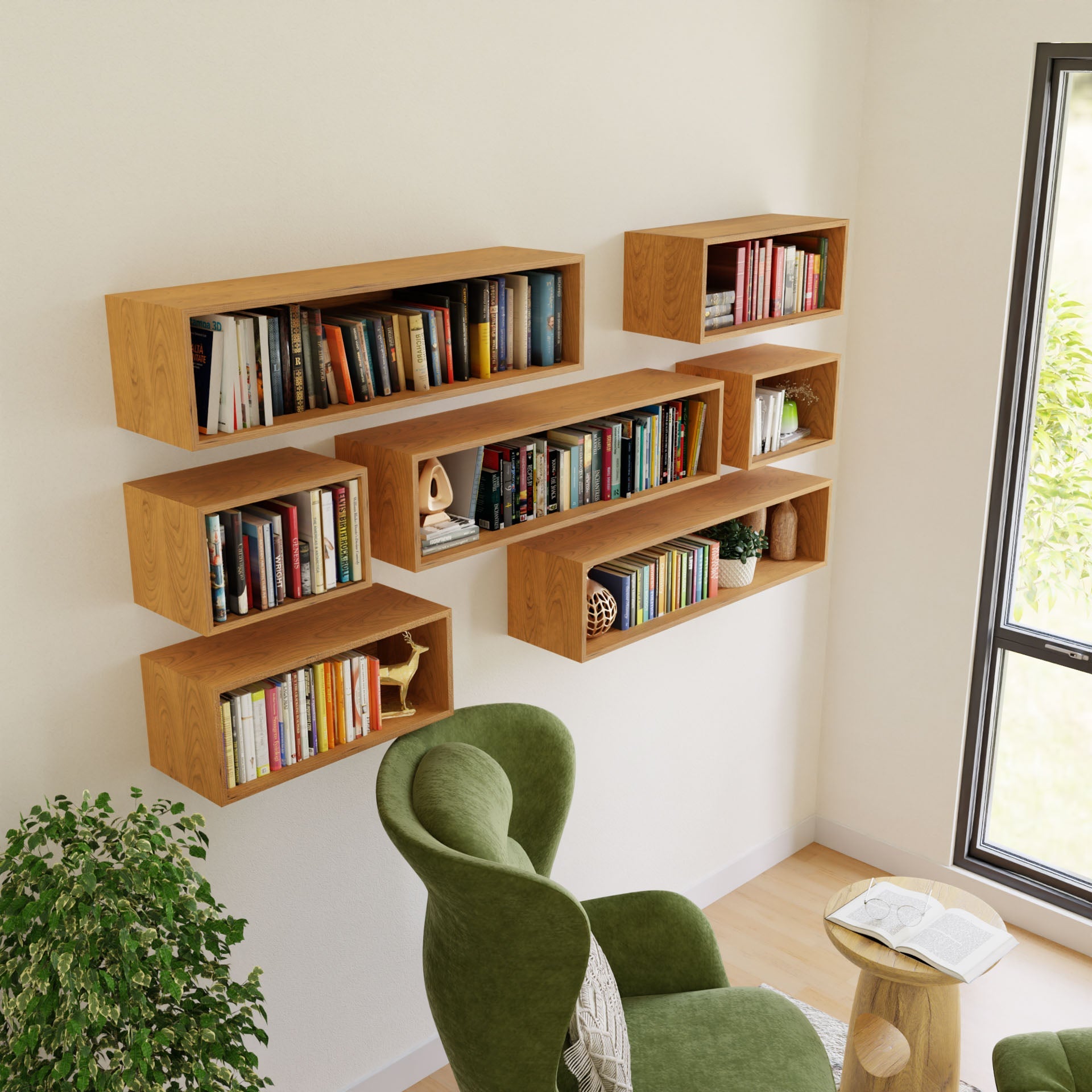 Krovel's Floating Bookshelf in Cherry, expertly mounted on the white wall, is filled with books and decor items. A cozy green chair faces a small American Cherry table by a large window, while a potted plant adds greenery to create an inviting reading nook.