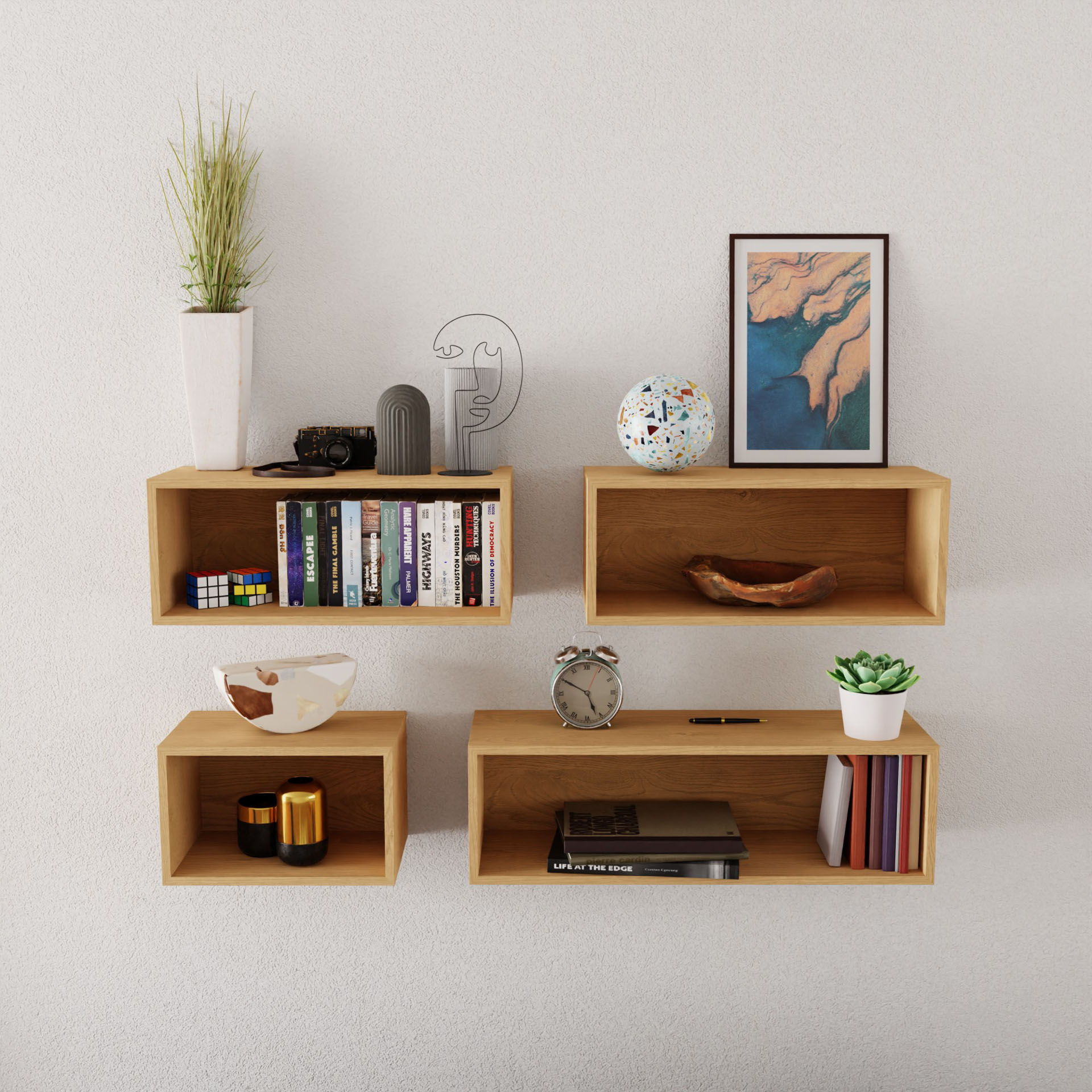 Four Krovel Floating Bookshelves in Maple enhance the wall, elegantly displaying books, a clock, small plants, two mugs, a Rubik's Cube, decorative items, and framed art. Constructed from American Hard Maple and installed using a French cleat system, this well-lit arrangement maintains a chic and organized aesthetic.