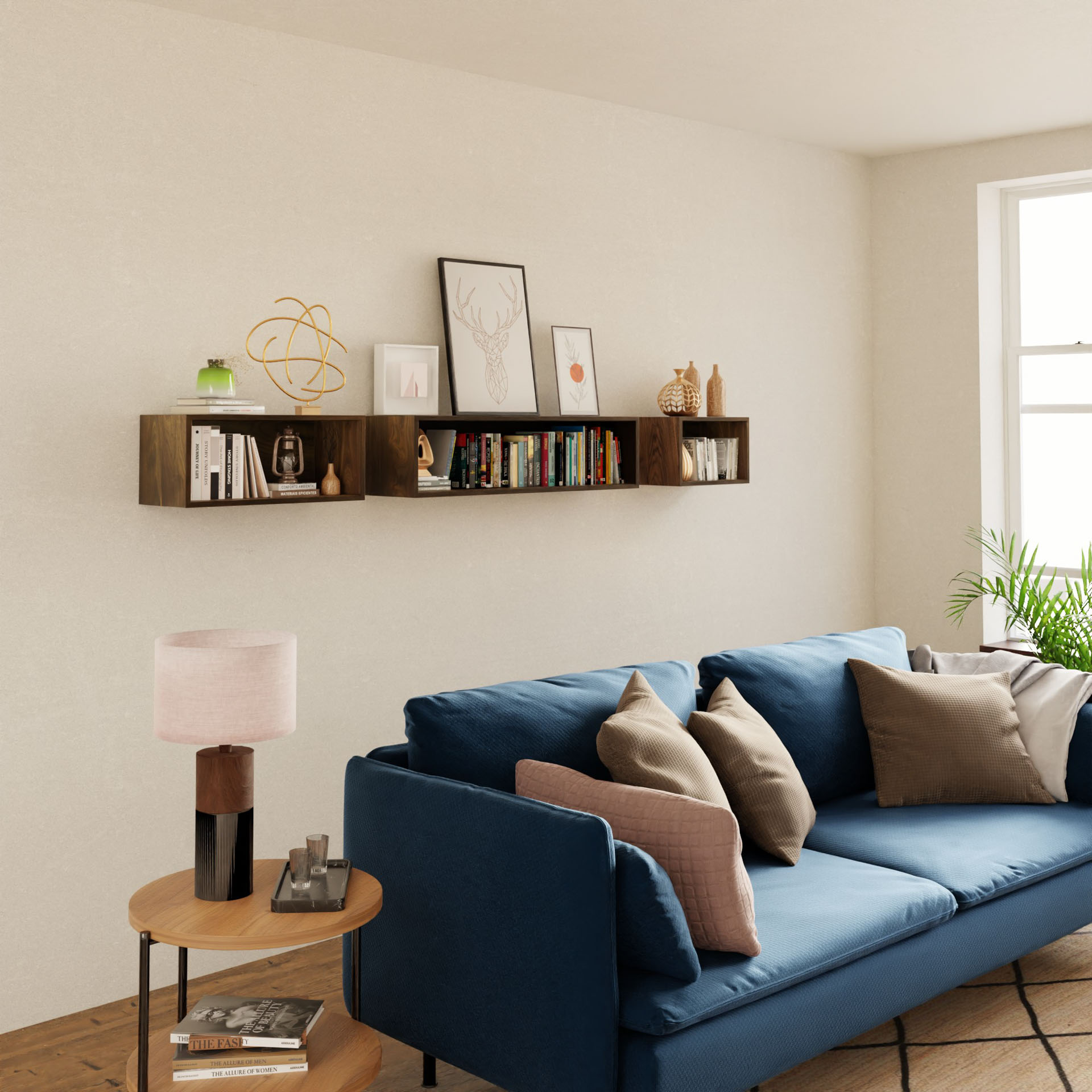 A modern living room showcases a blue sofa with assorted pillows. Behind it, Krovel's Floating Bookshelf in Walnut holds books, framed art, and decor. A small wooden side table supports a lamp and handmade plant pot, positioned near a large window.