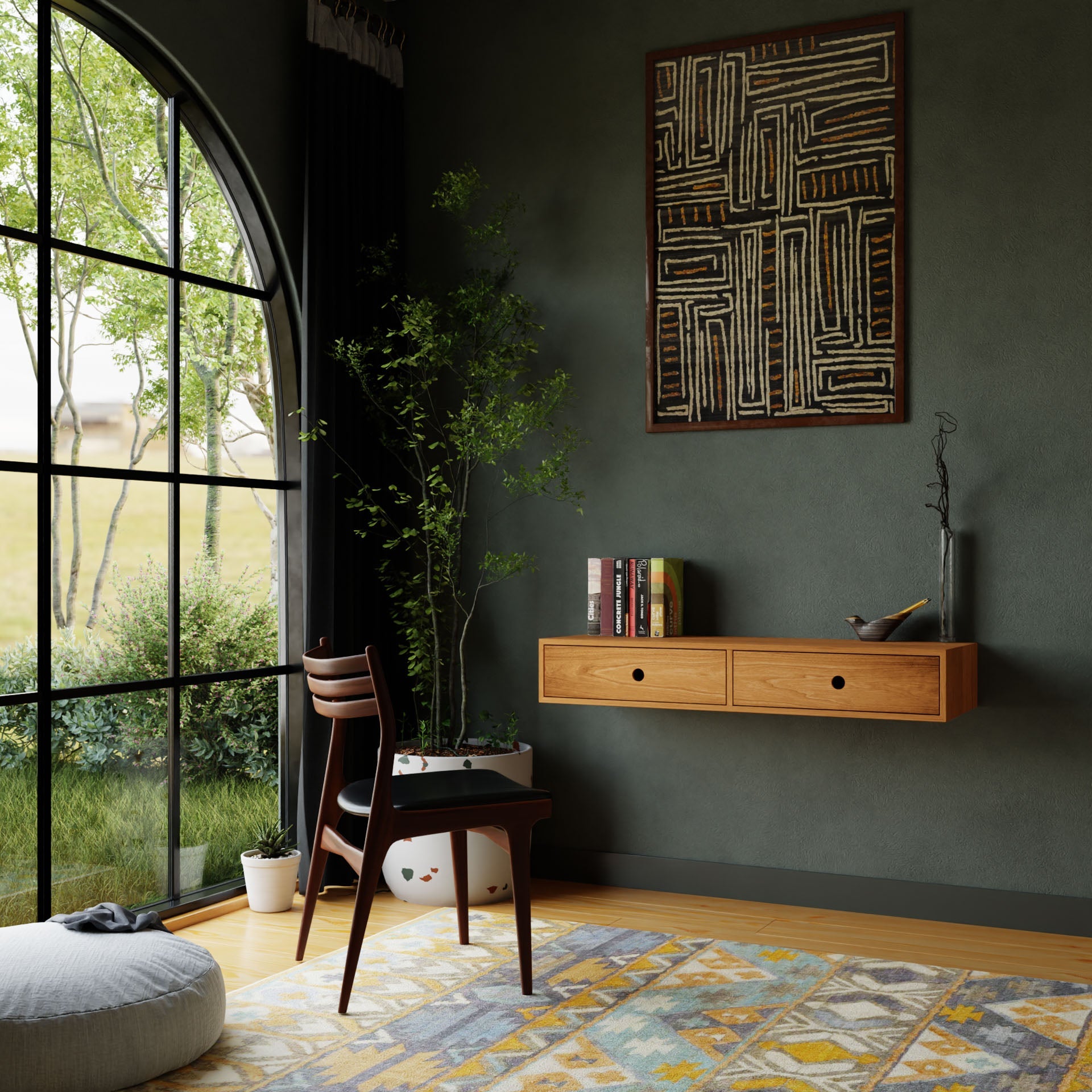 A cozy study area features a handmade wooden desk and chair by the window, providing a view of the garden. The room is adorned with dark green walls, geometric wall art, a potted plant, and a colorful rug. An elegant Floating Desk in Cherry from Krovel enhances the space alongside a small cushion on the floor nearby.