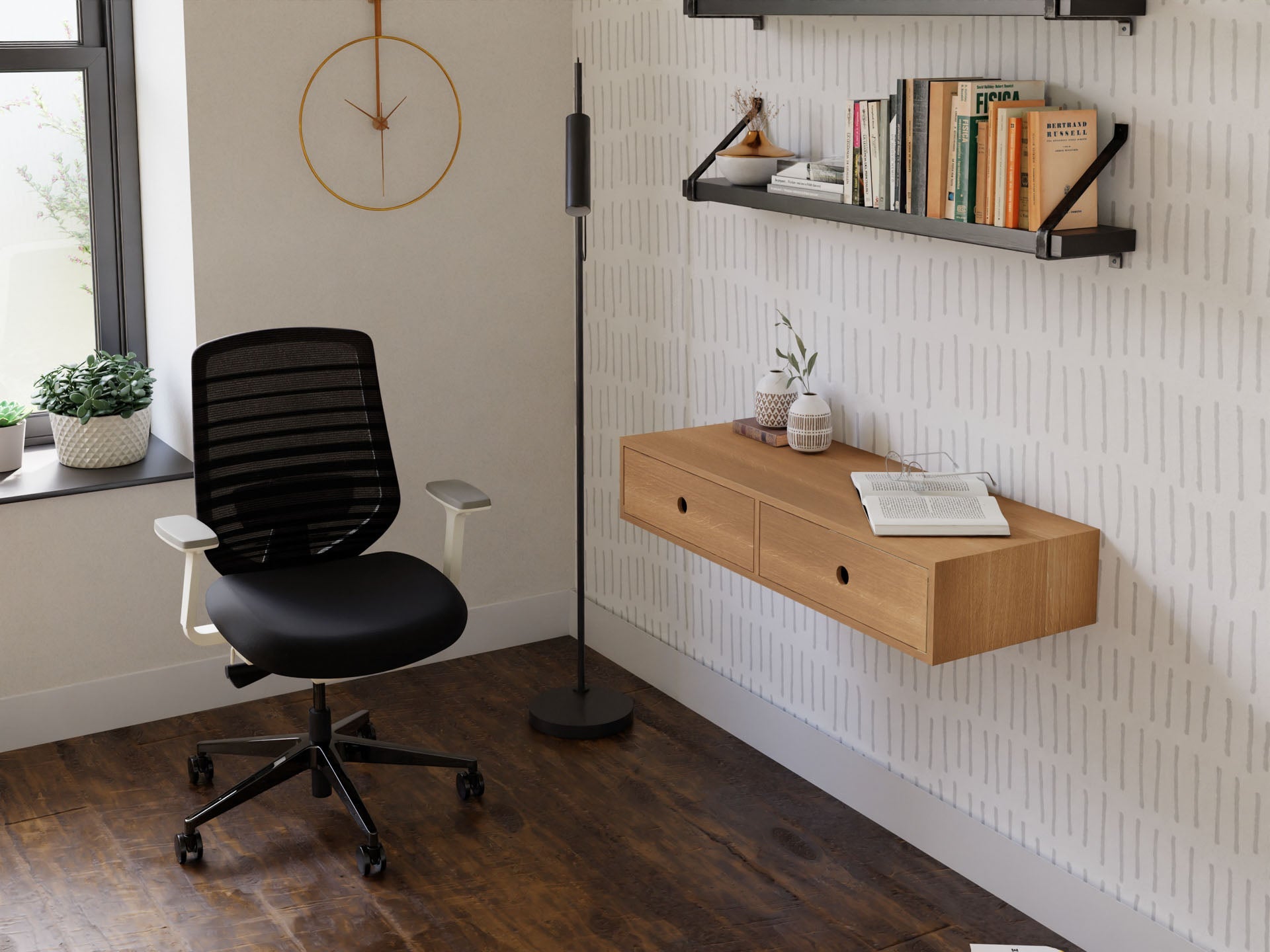 A modern home office includes a black office chair, a Krovel handmade floating desk crafted from White Oak with drawers, and a standing floor lamp. Two shelves filled with books and decor are mounted on a patterned wall. Sunlight streams through a window adorned with potted plants.