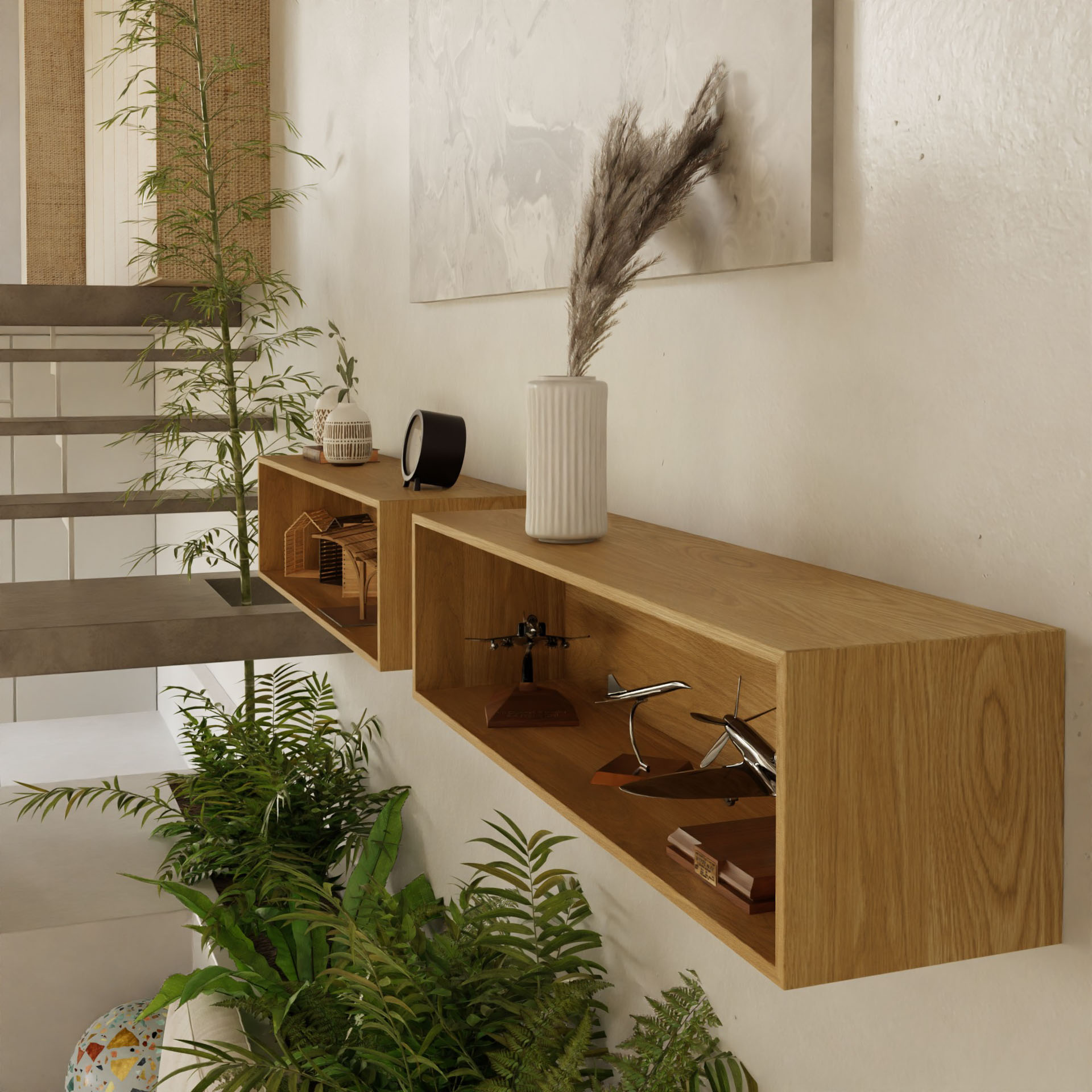 Two Krovel Floating Display Cases in White Oak are mounted with a French cleat system. They showcase a white vase with dried plants, black speaker, wooden model houses, and metal airplane model. Above them, solid oak frames neutral-toned wall art; below, green plants decorate the glass-railed staircase.