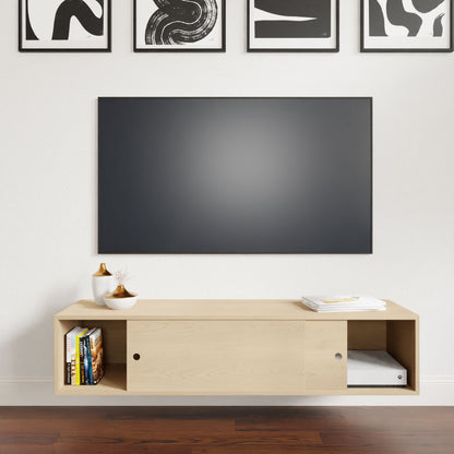 A minimalist living room highlights a large flat-screen TV mounted on a white wall. Below, a Krovel Oversized Media Console Table in Maple elegantly showcases books and decor. Above the TV are four abstract black and white art pieces, while the floor displays rich dark wood.