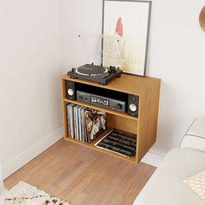 A turntable and stereo system enhance the Krovel Record and Stereo Storage Cabinet in Cherry, featuring a sleek Mid-Century Modern design and filled with vinyl records. A framed artwork rests against the wall behind the turntable. The elegant setup sits next to a white sofa on a wooden floor.