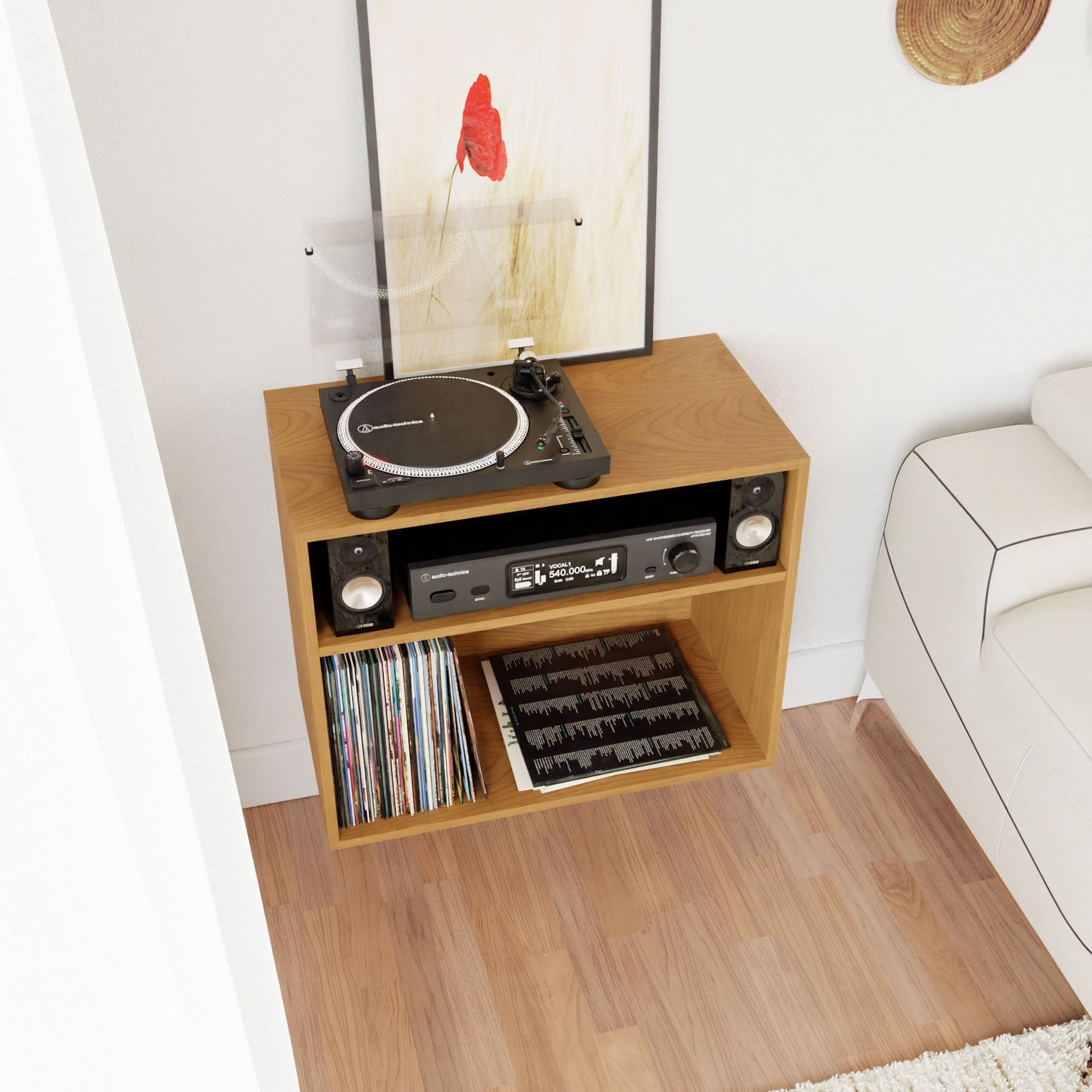 A Record and Stereo Storage Cabinet in Cherry by Krovel, crafted from solid American cherry, features a turntable with a clear dust cover on top, a stereo receiver on the middle shelf, and vinyl records stored in the bottom compartment. Above it hangs a minimalistic floral artwork that complements the Mid-Century Modern style, with part of a white sofa visible.