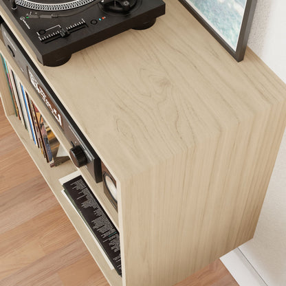 A Maple Record and Stereo Storage Cabinet by Krovel, featuring a turntable on top. Below, the shelves are stocked with vinyl records. Crafted in a stylish American Walnut finish, this cabinet radiates Mid-Century Modern charm as it stands elegantly on a hardwood floor.