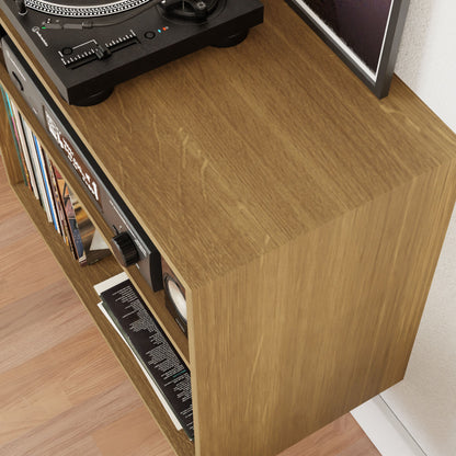 A Krovel Record and Stereo Storage Cabinet in White Oak exudes nostalgic charm, with a turntable and speaker on top. Its shelves overflow with vinyl records and books, perfectly complementing the rich American Walnut floor. A glimpse of a wall hints at classic design sensibilities.