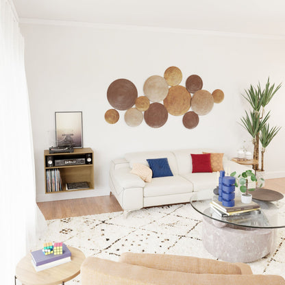 A cozy Mid-Century Modern living room showcases a white sectional sofa adorned with red and blue cushions. Geometric wall art is featured above, while a round glass coffee table complements the scene. The style is accentuated by Krovel's sleek Record and Stereo Storage Cabinet in White Oak, housing a record player. A tall plant and patterned rug complete the inviting space.