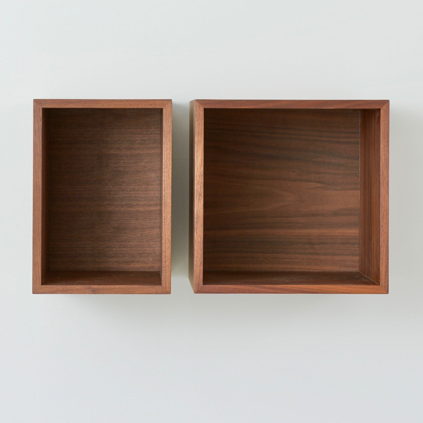 Two Record Storage Shelves in Walnut by Krovel, featuring visible grain patterns, are displayed side by side on a light background. The left, a smaller elongated box, is ideal for some vinyls, while the right is larger and square-shaped.