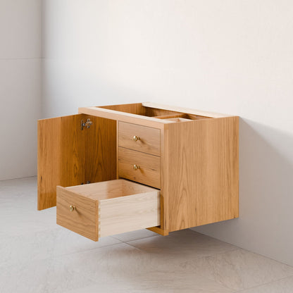 Krovel Furniture Co.'s floating Single Door, Triple Drawer Vanity in Cherry features a hardwood veneer with an open cabinet door on the left and center drawer. It has a light wood finish and is seamlessly mounted against a white wall above a tiled floor.