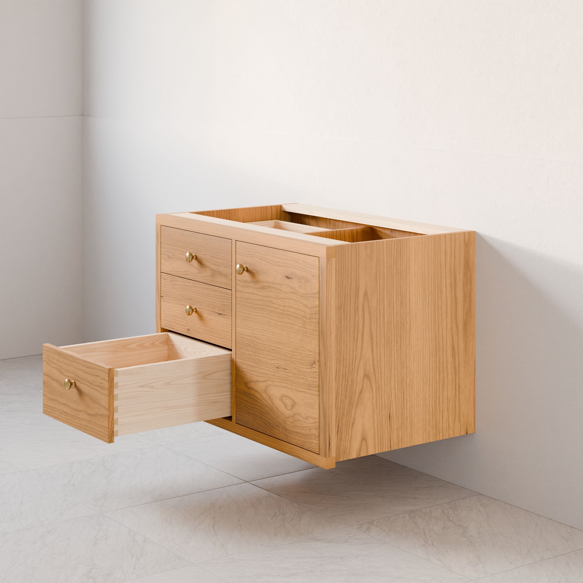 The Krovel Furniture Co.'s Single Door, Triple Drawer Vanity in Cherry offers a minimalist design with round brass handles, complemented by light-colored tile flooring. It features soft-close drawers and is mounted on a white wall with a natural wood finish.