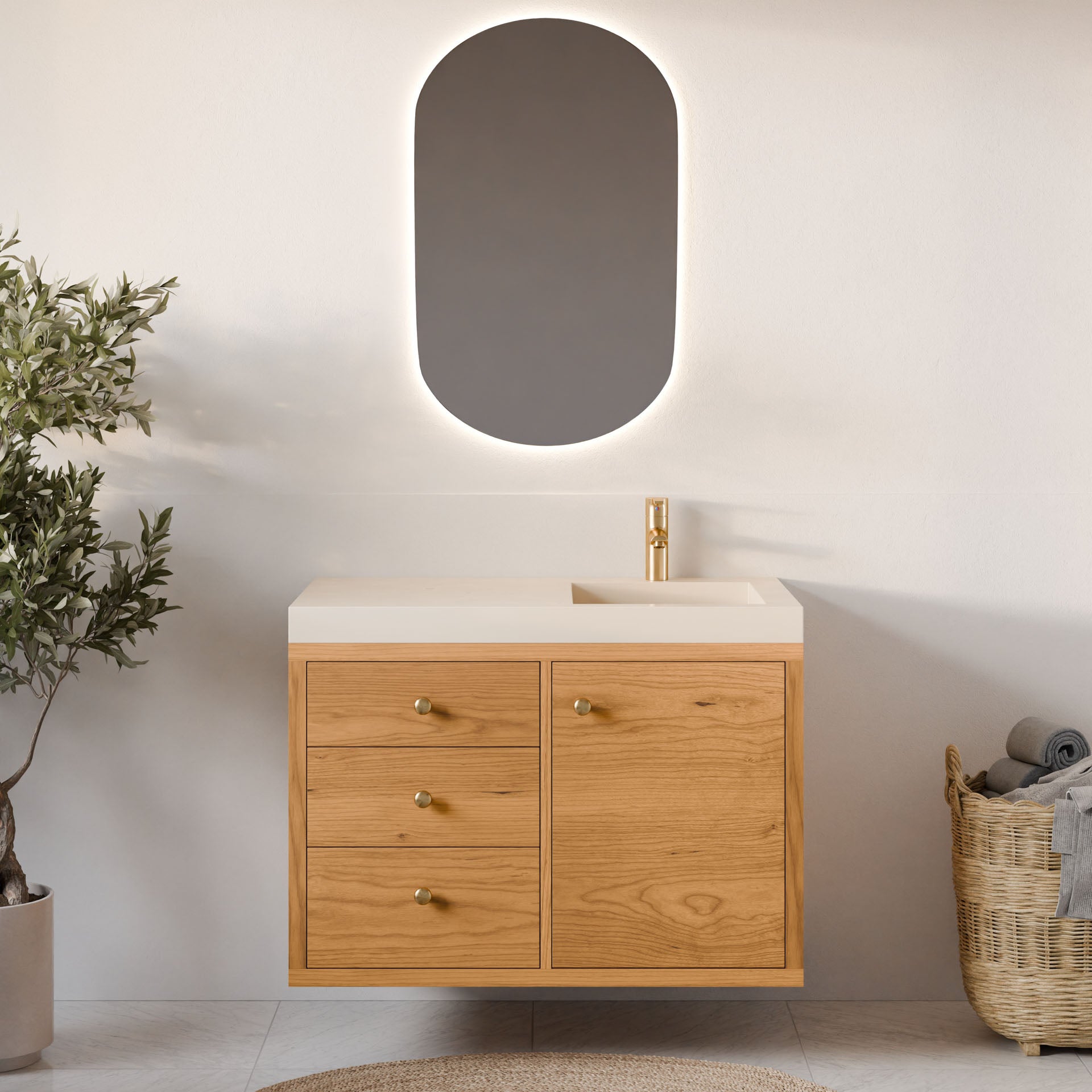 A modern bathroom features a wall-mounted Krovel Furniture Co. Single Door, Triple Drawer Vanity in Cherry with a single sink. An oval backlit mirror hangs above, complemented by a woven basket of towels and a potted plant for natural accents.#configuration_right-side-sink