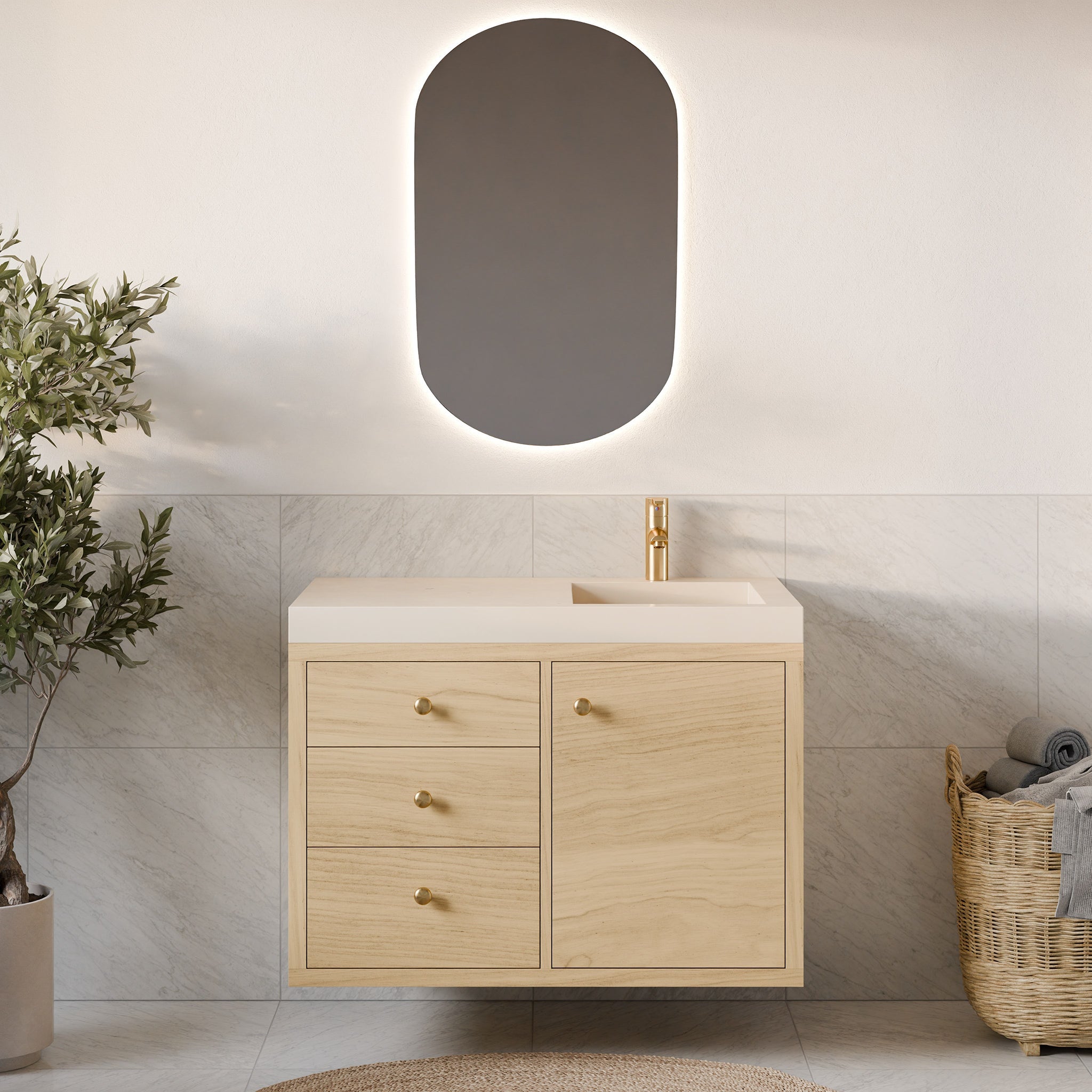 A minimalist bathroom highlights the Krovel Furniture Co. Single Door, Triple Drawer Vanity in Maple with its floating design, hardwood veneer, and soft-close drawers. Brass knobs, an oval mirror's gentle glow, a potted plant, and towels in a wicker basket enrich the neutral beige tile palette.