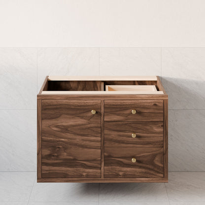 The Single Door, Triple Drawer Vanity in Walnut by Krovel Furniture Co. features an open top and has soft-close hinges on its door and three drawers with round brass handles. It’s beautifully set against a tiled wall and floor in pale, neutral tones.